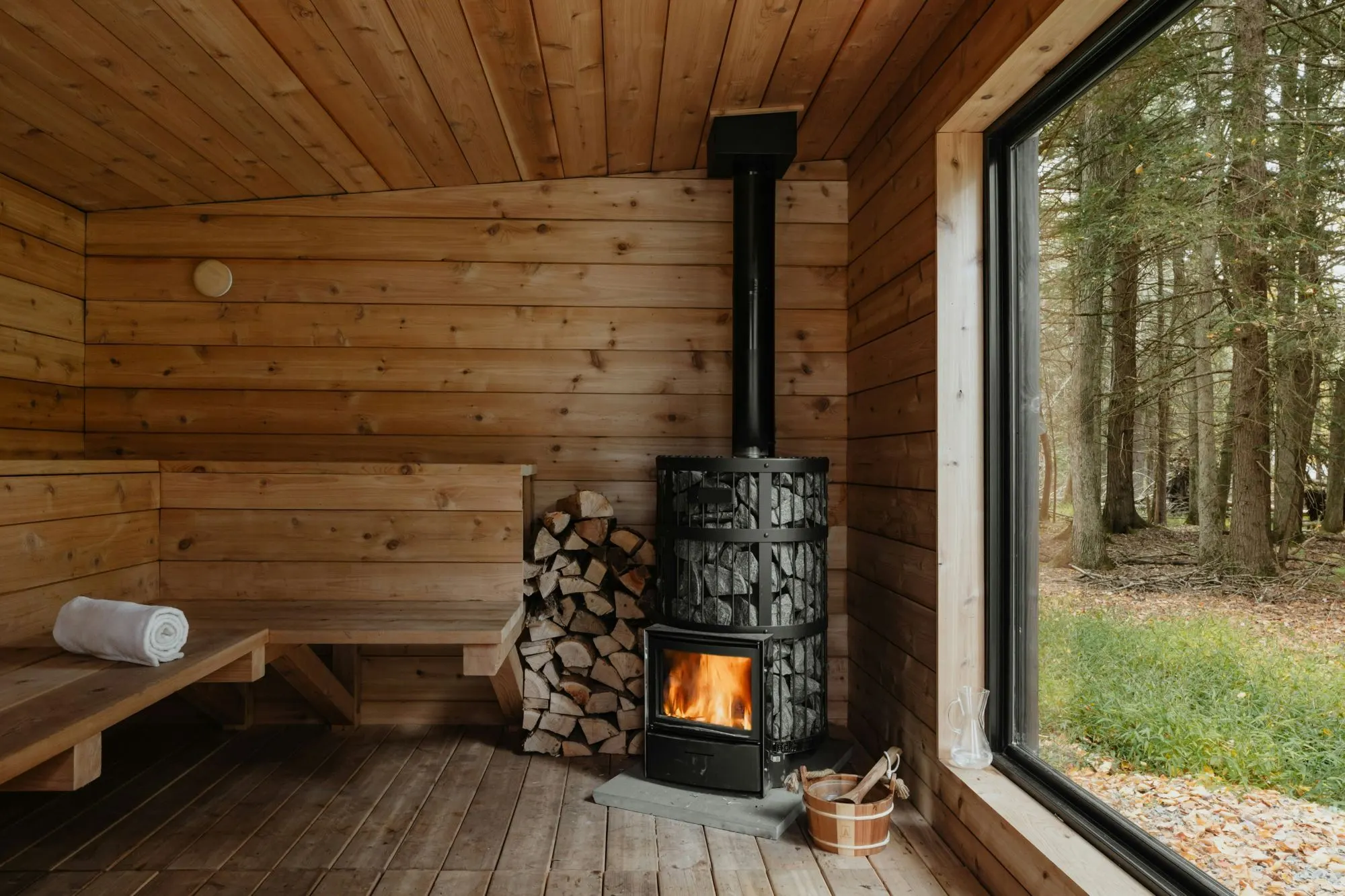 Eine Holzsauna mit Ofen und Blick in den Wald